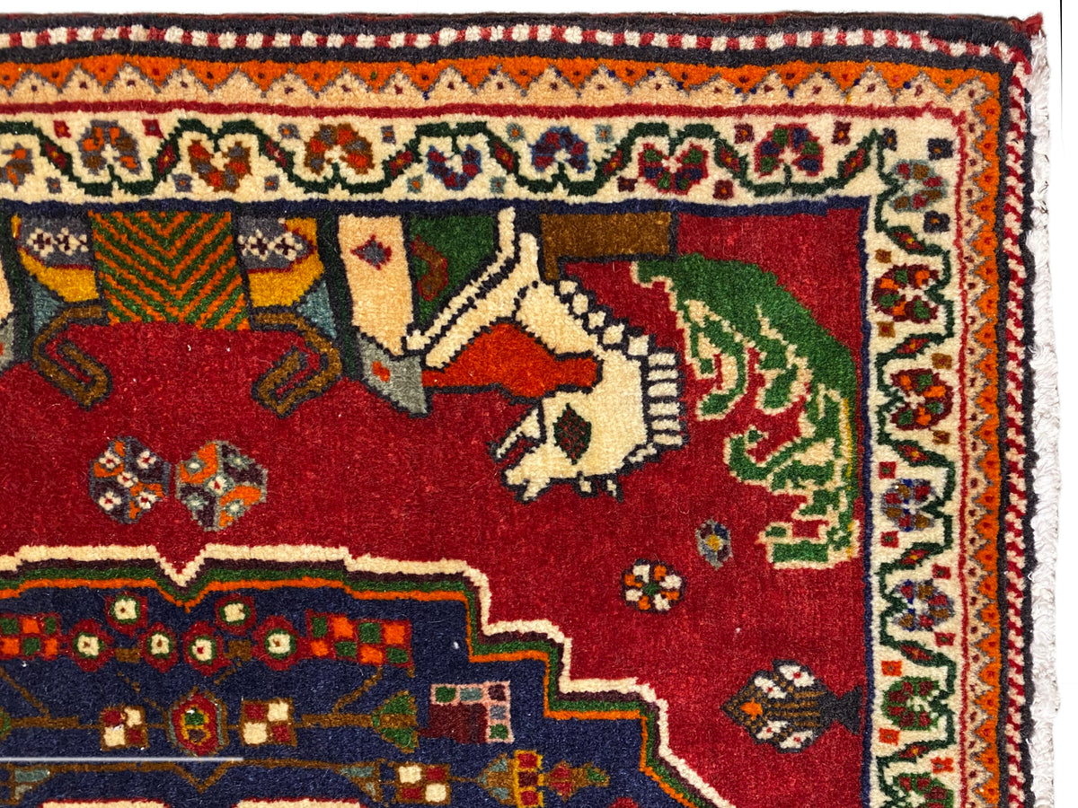 Primo piano di un tappeto Poshti, campo rosso con animali, bordo decorativo blu e bordatura a motivi