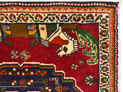 Primo piano di un tappeto Poshti, campo rosso con animali, bordo decorativo blu e bordatura a motivi