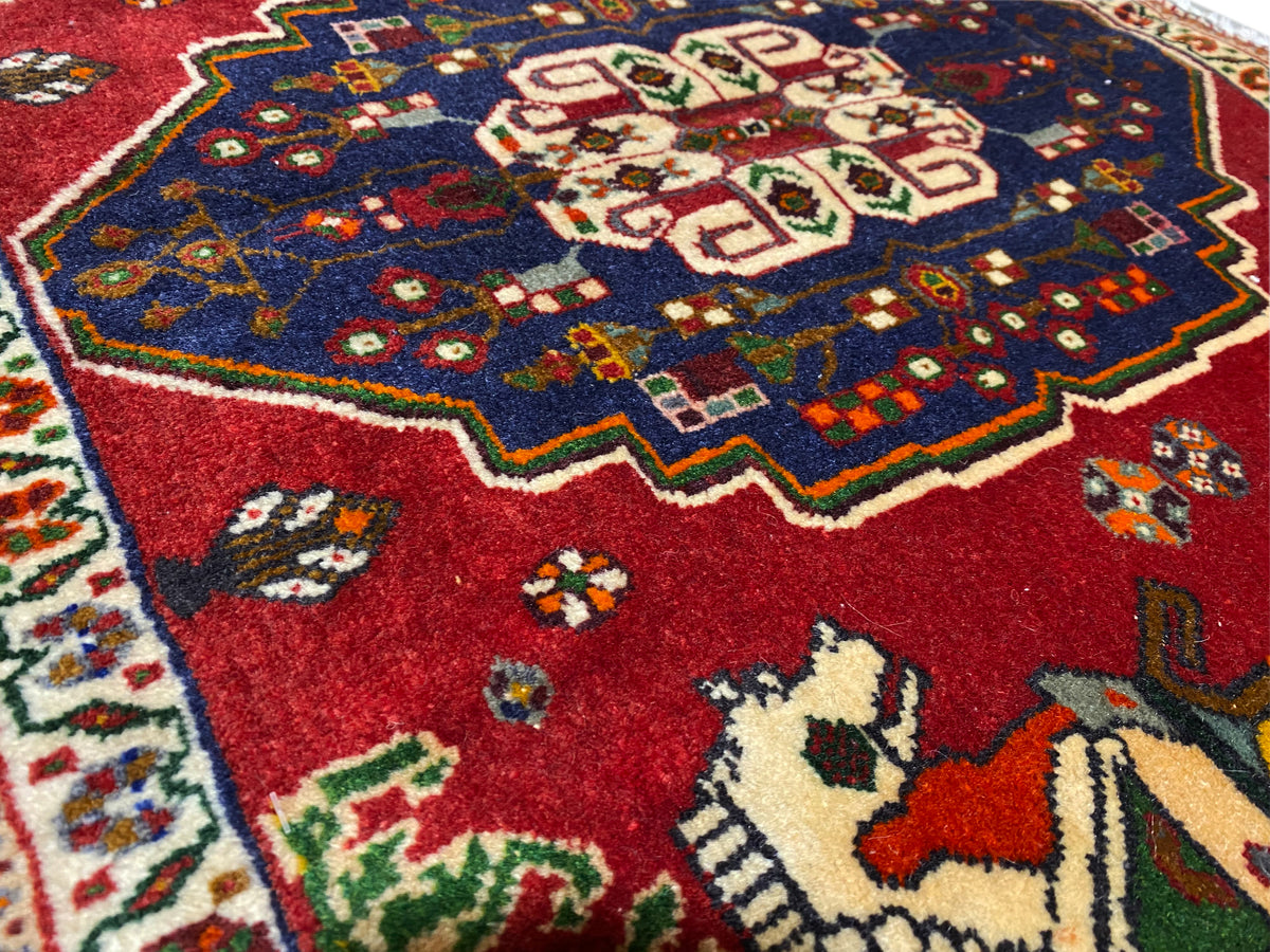 Primo piano di un tappeto Poshti, campo rosso con corona ornamentale blu e motivi animali