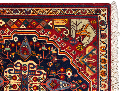 Primo piano del bordo del tappeto con campo ornamentale blu, dettagli rossi e frange