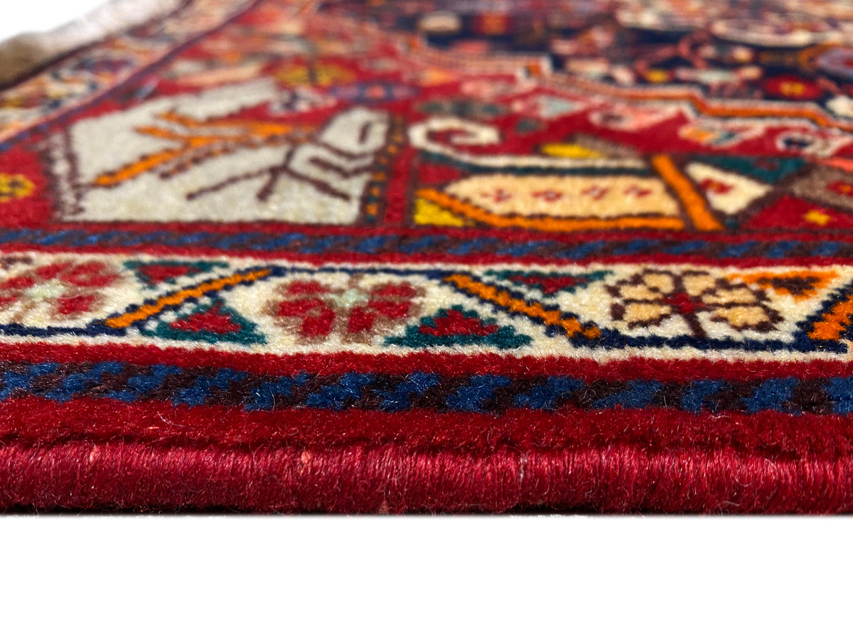 Dettaglio del tappeto sul bordo: bordura rosso-blu, motivi multicolori e frange corte