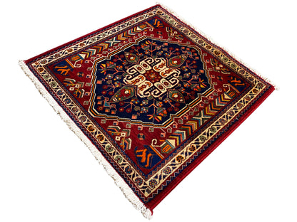 Tappeto 63x60 cm con vista diagonale: centro blu scuro, bordo rosso, frange