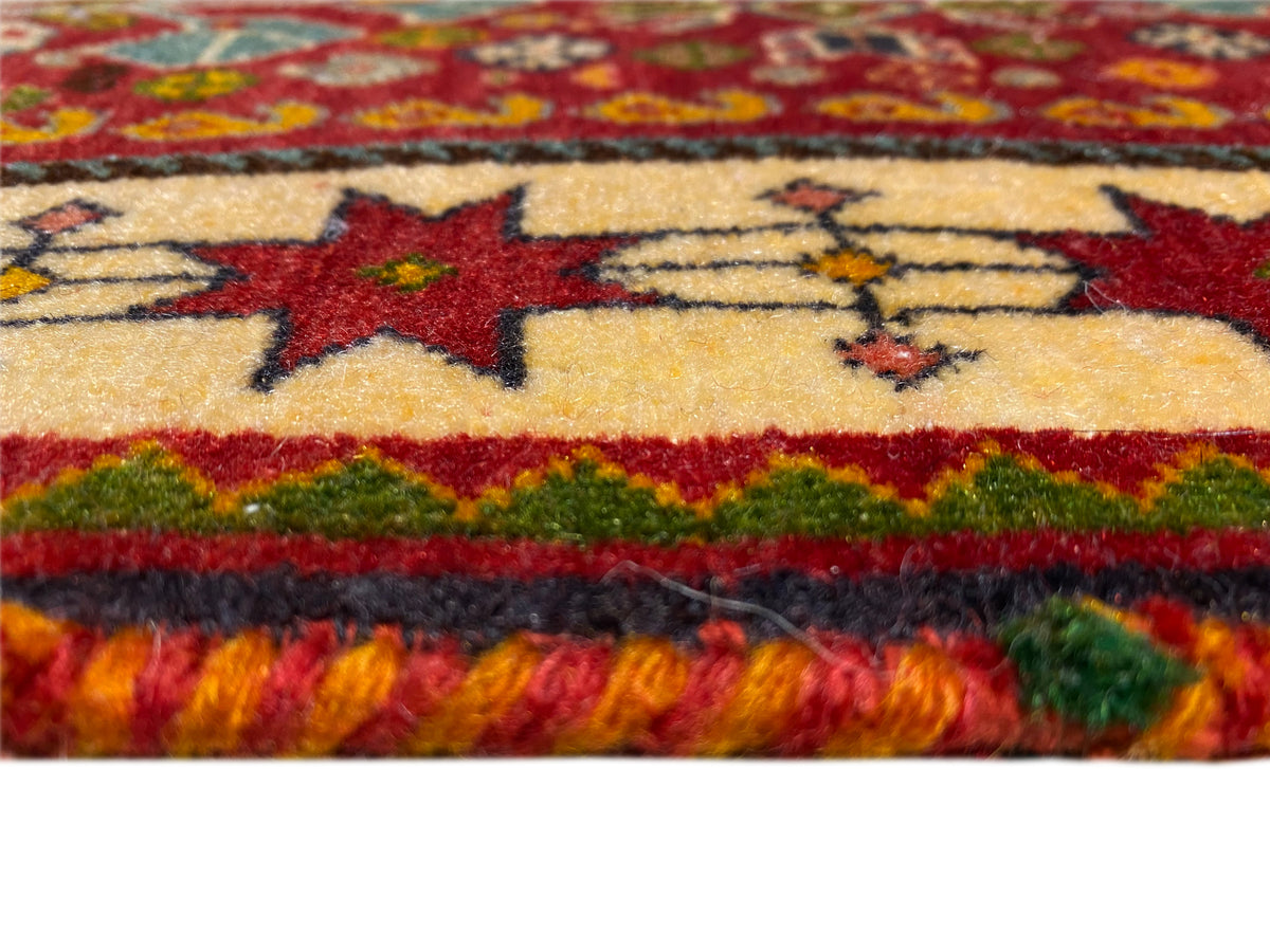 Bordo del tappeto in dettaglio: stelle rosse su fondo beige, linea verde e frange