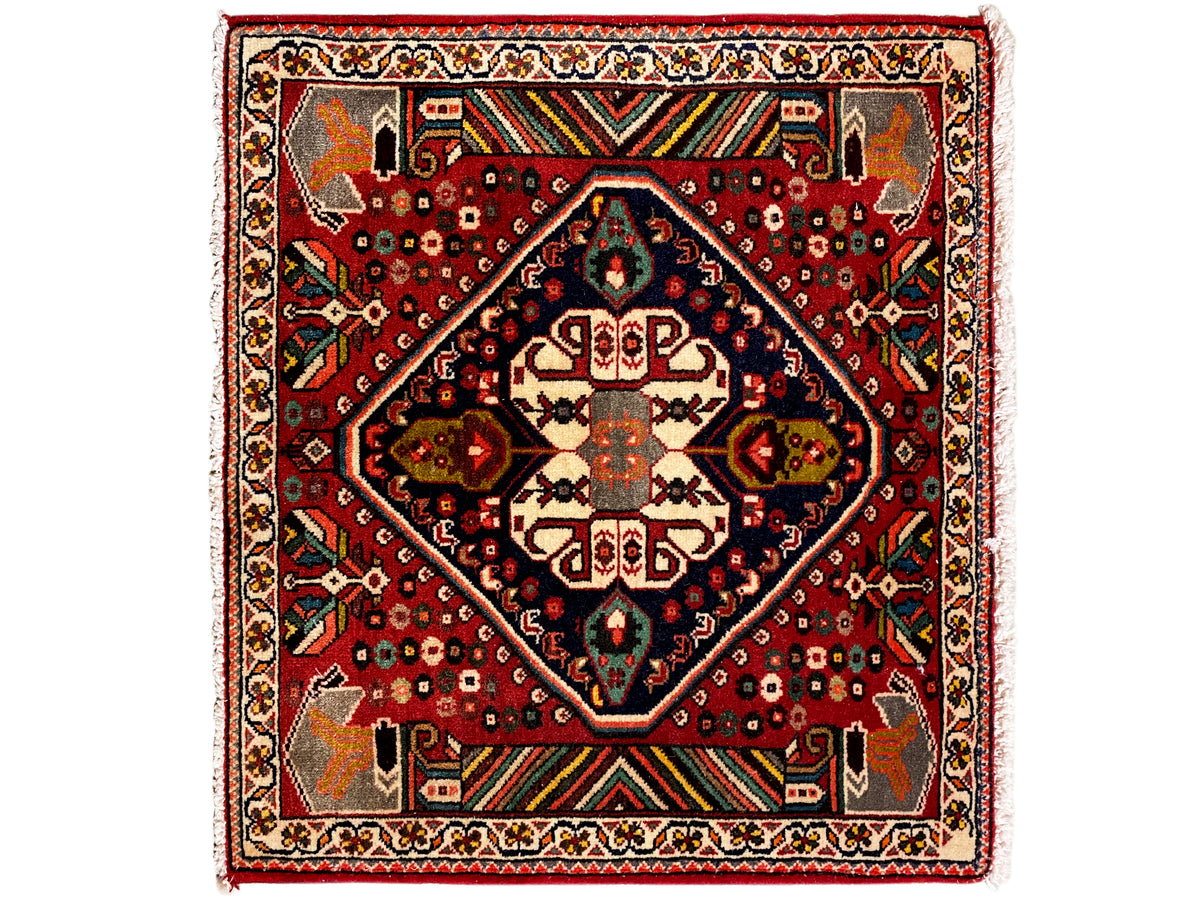 Tappeto orientale con fondo rosso, medaglione blu scuro e ornamenti geometrici