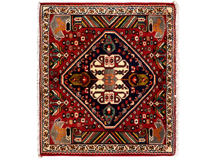 Tappeto orientale con fondo rosso, medaglione blu scuro e ornamenti geometrici