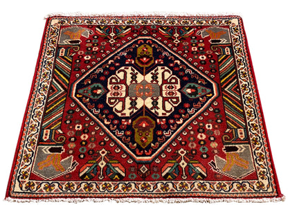 Tappeto orientale rettangolare con motivo rosso, bordo interno blu e ornamenti sui bordi