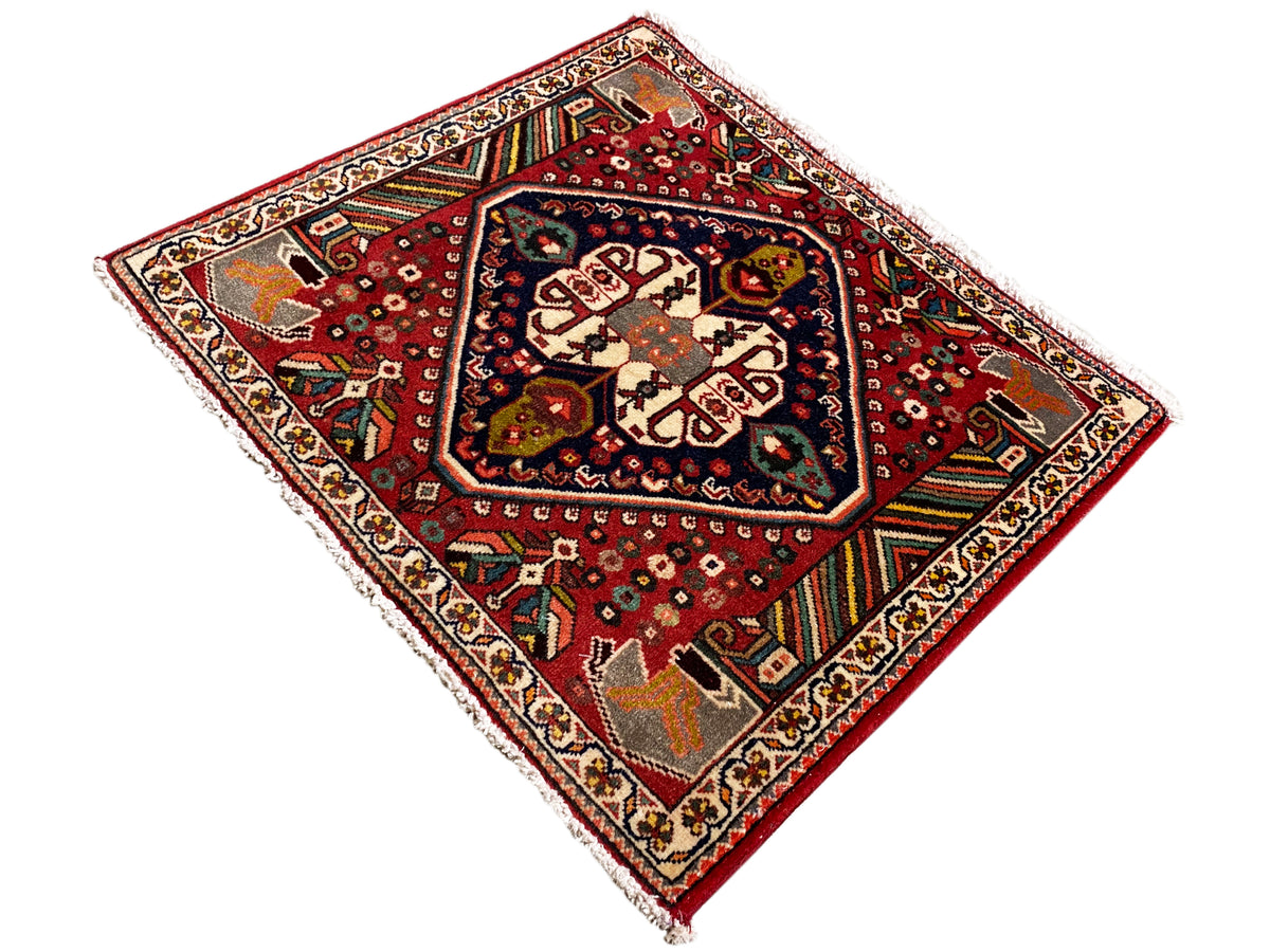 Tappeto orientale con sfondo rosso, motivi color crema e bordi ornamentali colorati