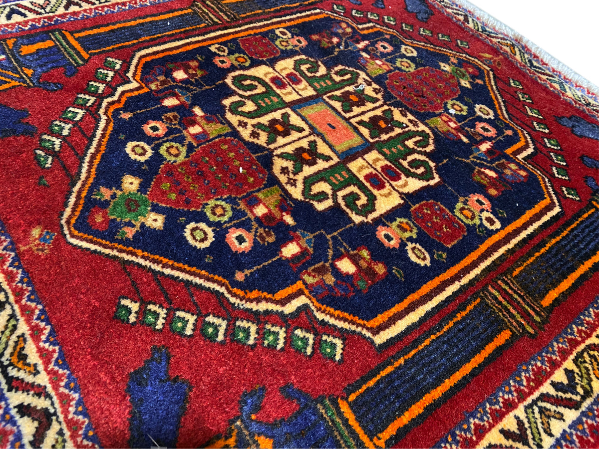 Tappeto Poshti 66x62 cm Dettagli: motivo centrale rosso, campo blu e linee decorative colorate.