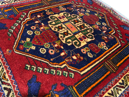 Tappeto Poshti 66x62 cm Dettagli: motivo centrale rosso, campo blu e linee decorative colorate.