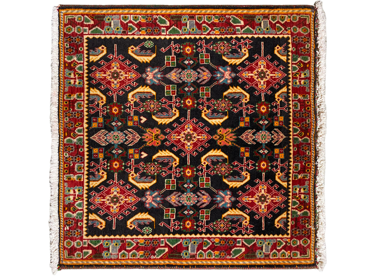Tappeto con motivo ornamentale quadrato, base nera, tonalità di rosso, giallo e verde