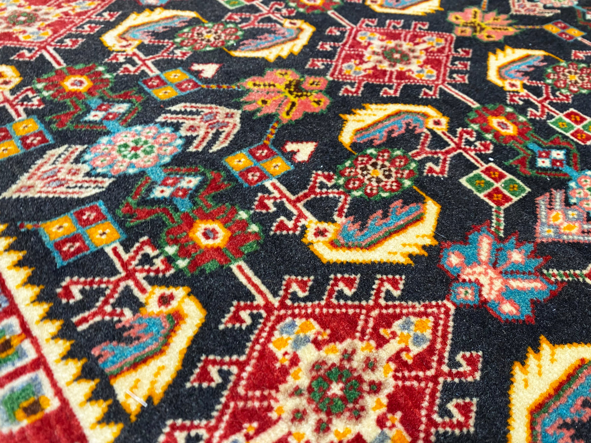 Superficie del tappeto con motivo geometrico colorato, nero, rosso, verde e giallo