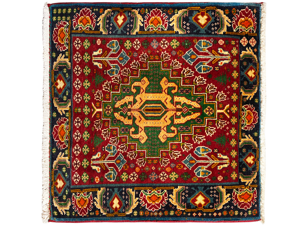 Tappeto rettangolare (67x66 cm) con fondo rosso, bordo decorativo scuro e motivo geometrico