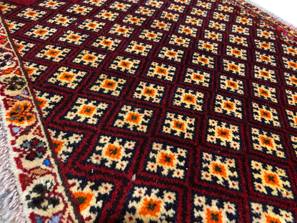 Tappeto Poshti 61x59 cm: primo piano del motivo con rombi colorati su fondo rosso scuro