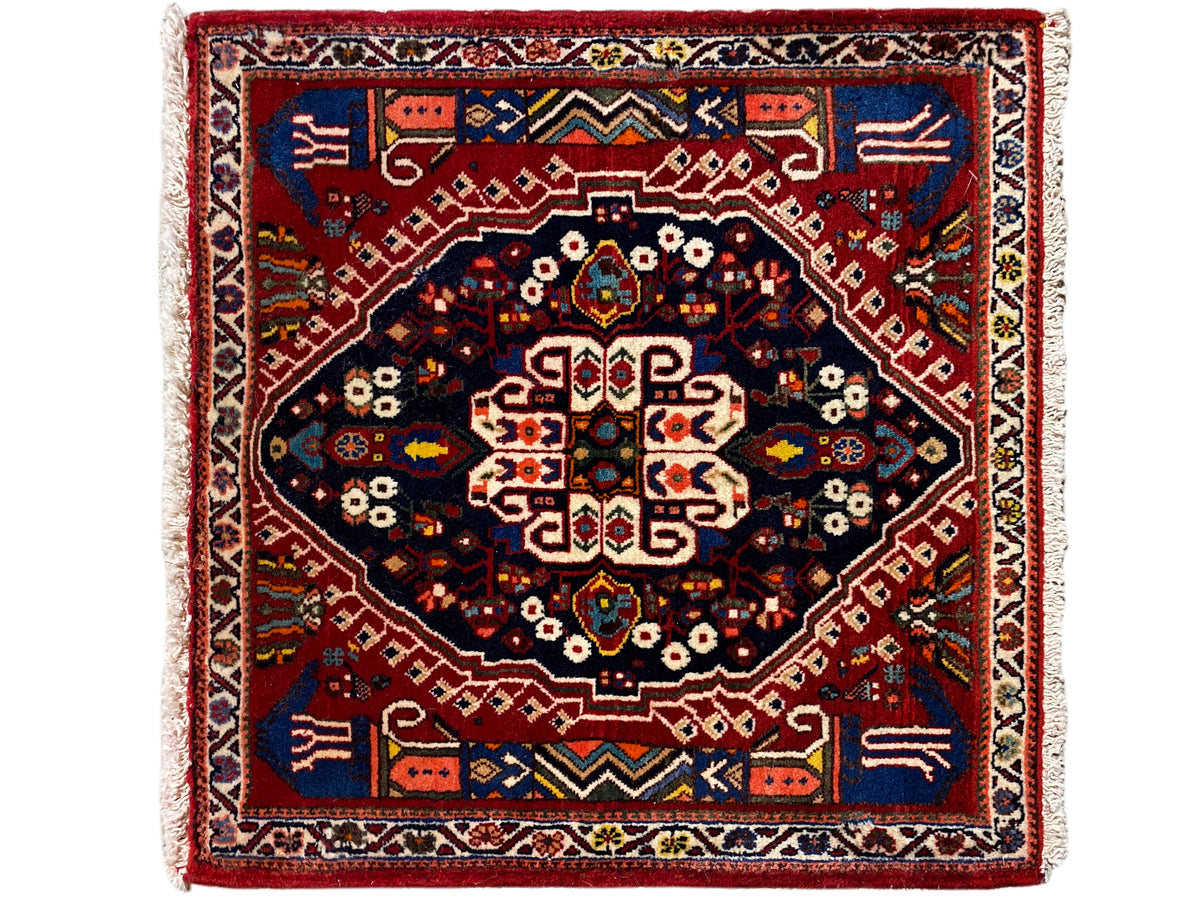 Tappeto rettangolare con bordo rosso, campo interno blu scuro e motivo geometrico