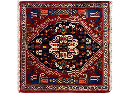 Tappeto rettangolare con bordo rosso, campo interno blu scuro e motivo geometrico