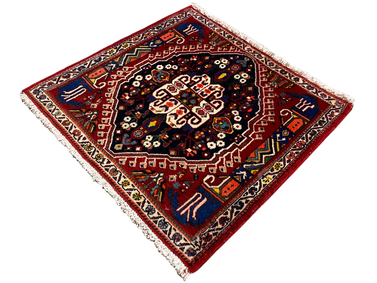 Tappeto con bordo rosso e centro blu scuro, ornamento a forma di stella, frange
