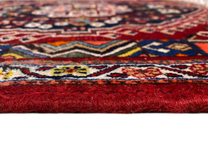 Dettaglio di un tappeto con motivo colorato e bordo con pelo alto rosso