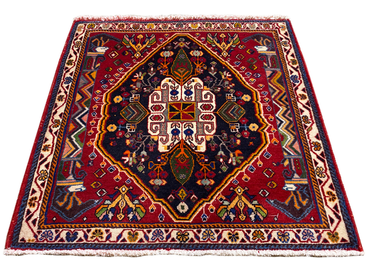Tappeto Poshti (67×67 cm) in vista obliqua: bordo, centro rosso, blu scuro