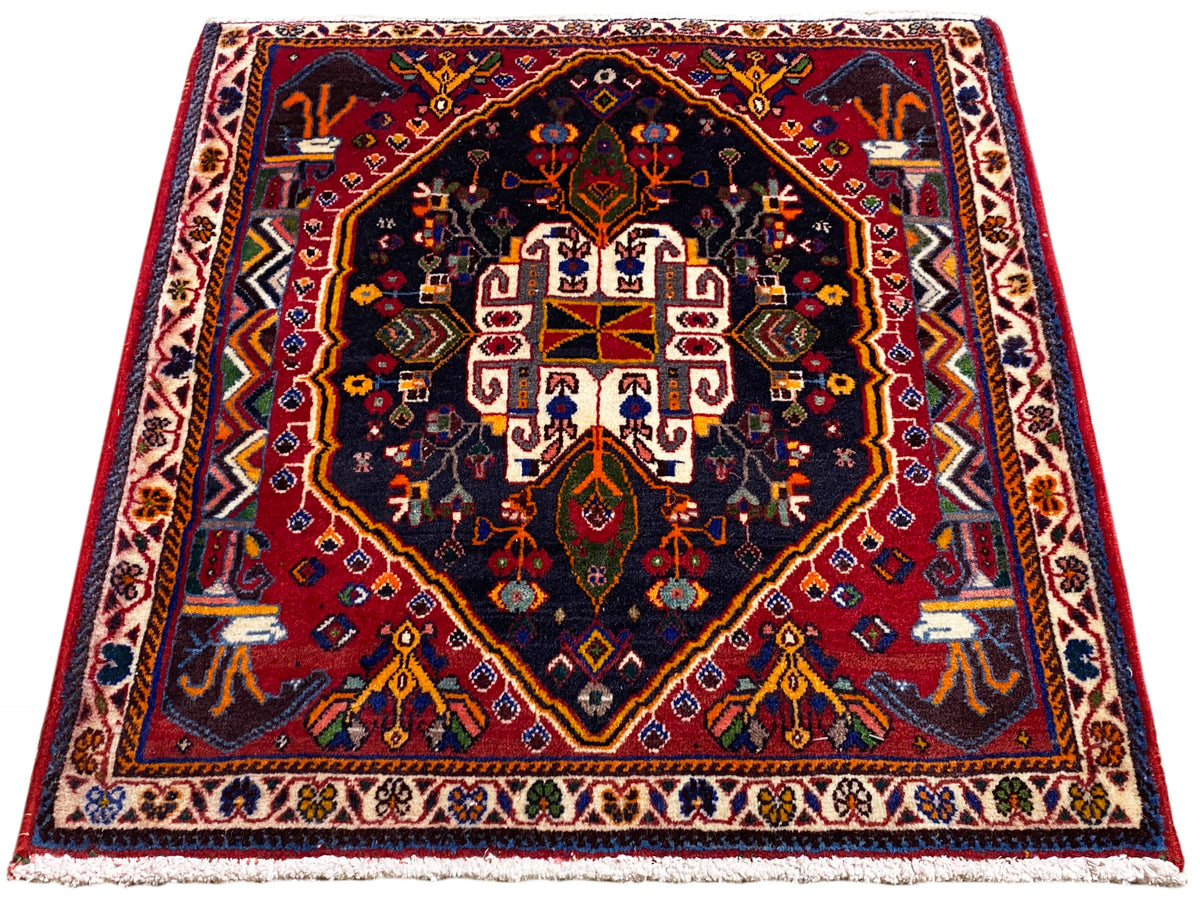 Tappeto 70x67 cm con fondo blu scuro, bordo rosso e motivo a medaglioni simmetrici