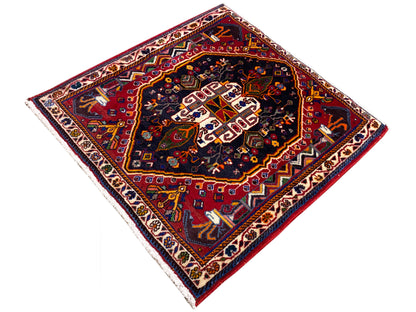 Tappeto 70x67 cm: motivo ornamentale scuro al centro, palette cromatica rosso-blu, bordura laterale