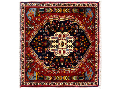 Tappeto Poshti 65x61 cm con bordo rosso, motivo centrale scuro e ornamenti colorati