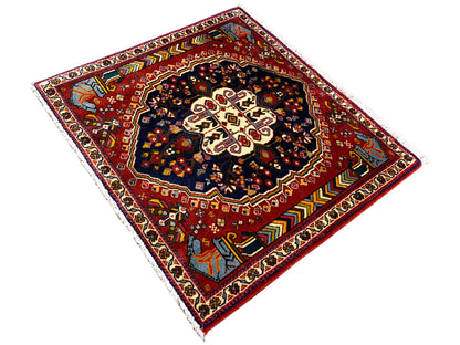Tappeto Poshti 65x61 cm, vista diagonale: campo rosso con motivo scuro e ornamenti sui bordi
