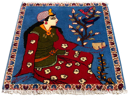 Tappeto Poshti 65x63 cm con motivo fiabesco, superficie blu, parte centrale rossa e frange