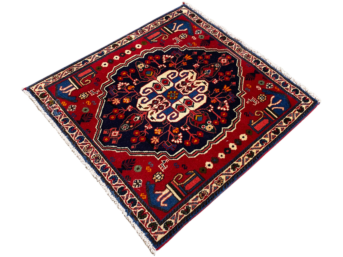 Tappeto quadrato con centro rosso, bordo blu e fascia ornamentale raffinata
