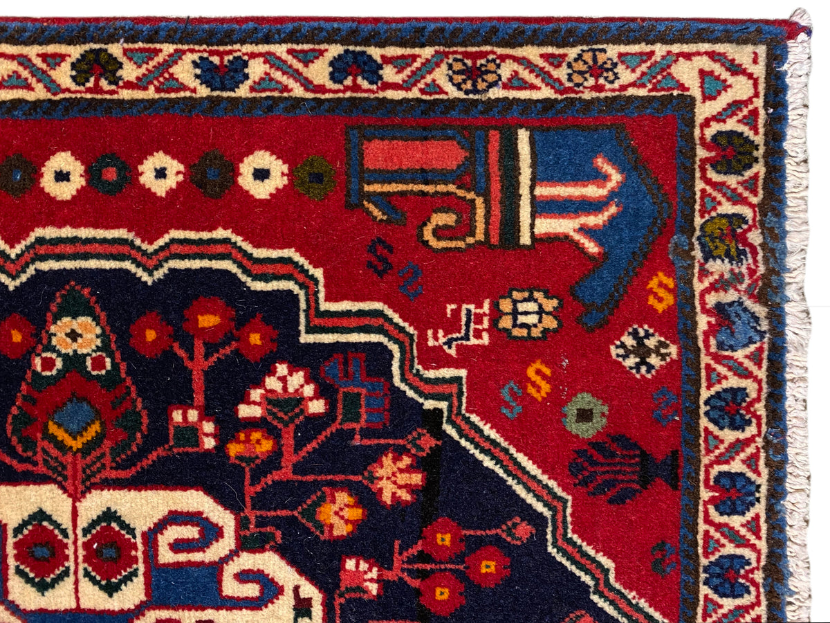 Angolo di tappeto con fondo rosso, simboli colorati e bordo decorativo blu