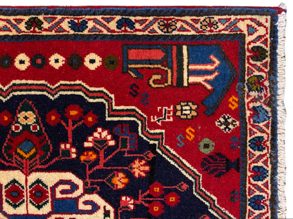 Angolo di tappeto con fondo rosso, simboli colorati e bordo decorativo blu